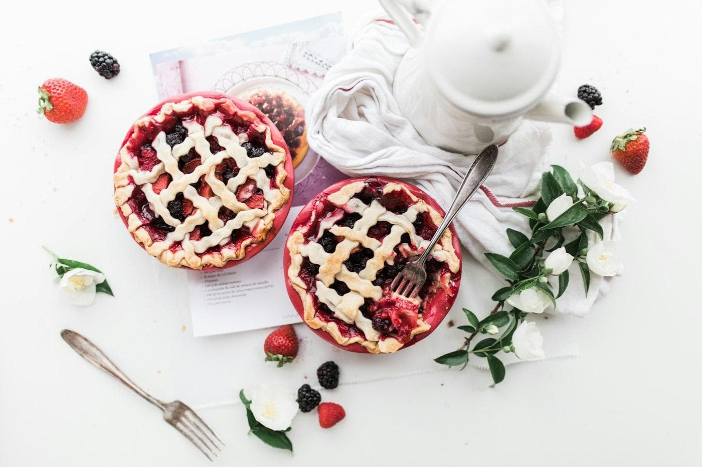 Tartelettes aux fruits rouges et théière sur une table blanche